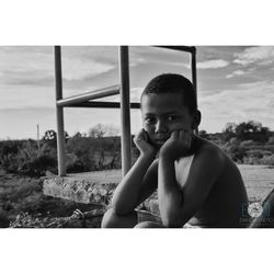 Portrait of boy sitting against sky