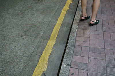 Low section of woman standing on footpath