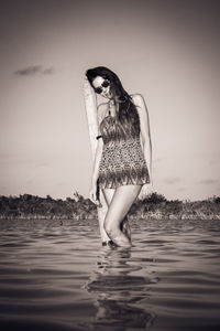 Full length portrait of woman standing at beach against sky