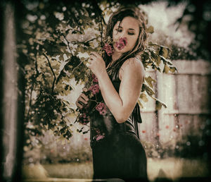 Woman standing by tree against plants