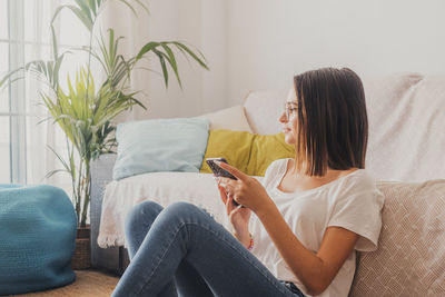 Midsection of woman using mobile phone while sitting on sofa at home