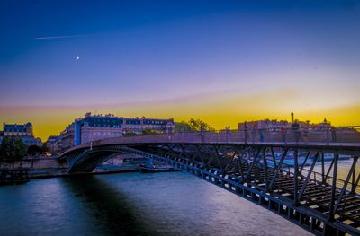 Bridge over river in city at dusk