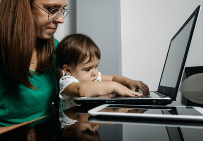 Rear view of mother and daughter using smart phone