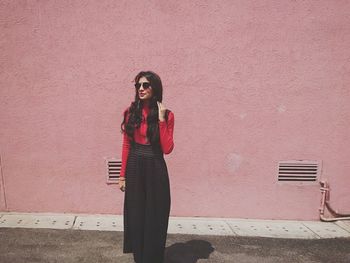 Portrait of young woman leaning against wall