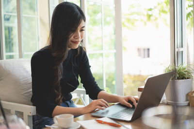 Smiling businesswoman working on laptop in cafe