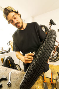 Young man repairing bicycle tire at table in workshop