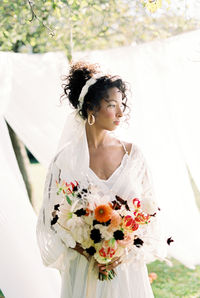 Bride holding bouquet standing outdoors