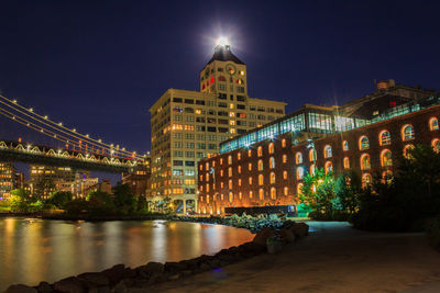 Cropped bridge over river by illuminated clock tower at dumbo during night
