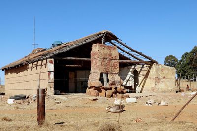 Damaged building on field against clear blue sky