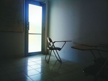 Empty chair and table by window at home