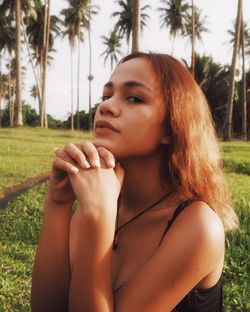 Portrait of young woman looking away against plants