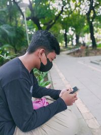 Side view of teenage boy using mobile phone