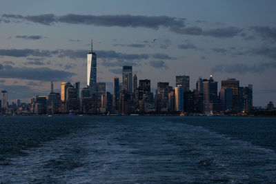 Lower manhattan skyline at sunset viewed from the water.