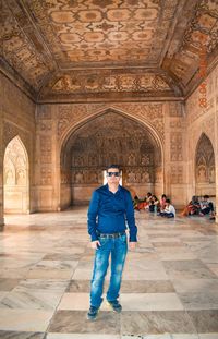 Full length portrait of man standing at historical building