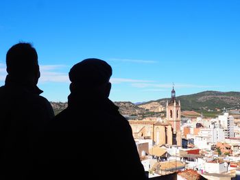 Rear view of man and buildings against sky