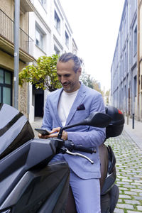 Mature businessman using smart phone sitting on motorcycle