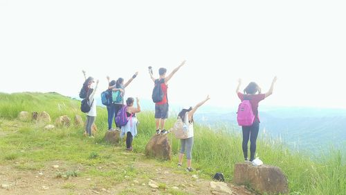 Low angle view of friends jumping against clear sky