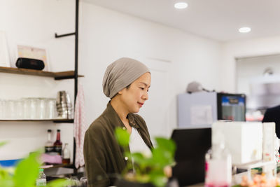 Woman restaurant owner standing at counter receiving orders.