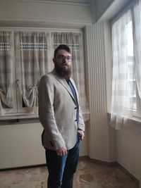 Young man standing by window at home