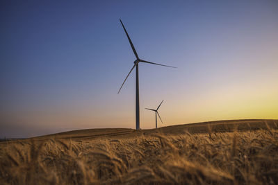 Windmill on field against sky during sunset