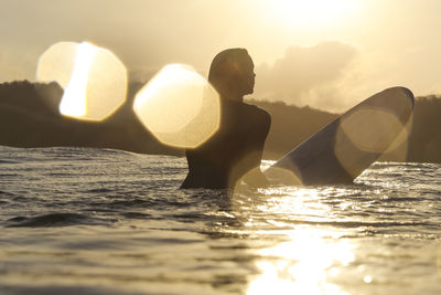 Female surfer in the ocean at sunset