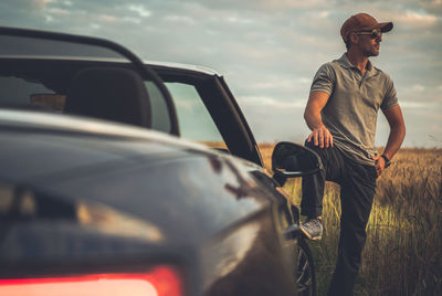 Man looking at camera while standing by car