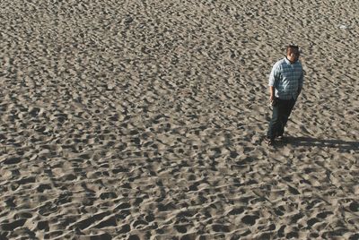 High angle view of man standing on sandy at beach