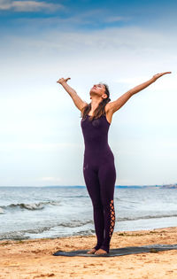 Full length of man with arms raised on beach against sky