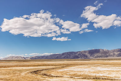 Arid plains against sierra nevada mountains and blue sky with clouds owens river valley