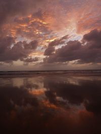 Scenic view of sea against dramatic sky during sunset