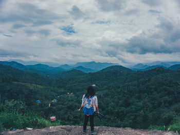 Rear view of man standing on mountain against sky