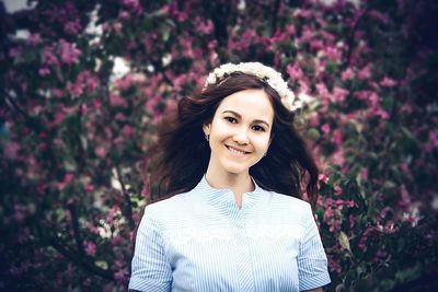 Portrait of young woman standing against trees