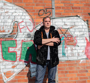 Fashionable mature man standing against graffiti wall