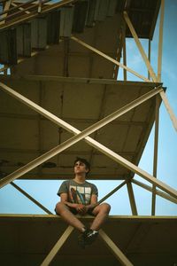 Portrait of young man standing against railing