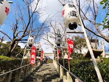 Lanterns hanging on bare tree against sky