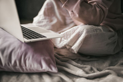 Midsection of man using laptop on bed at home