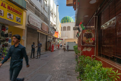 Full length of woman walking on footpath amidst buildings in city