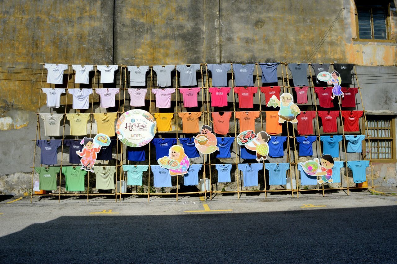 built structure, architecture, building exterior, multi colored, art and craft, street, art, creativity, graffiti, wall - building feature, in a row, human representation, day, outdoors, side by side, sidewalk, no people, variation, road, store