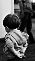 Rear view of boy with hands behind back while standing on field