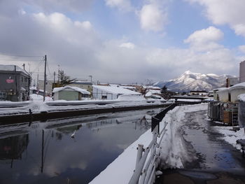 Panoramic view of frozen river by buildings against sky