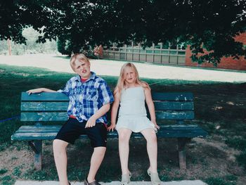 Full length of friends sitting on bench