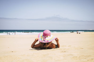 Woman wearing hat on beach against sky