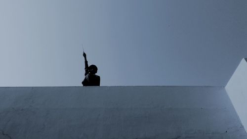 Silhouette man with arms raised against sky
