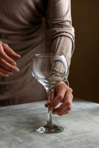 Unrecognizable female standing at table with crystal glass preparing for cocktail