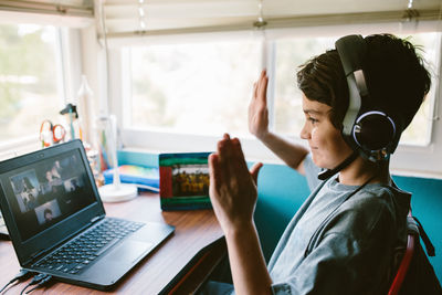 Boy waves to teacher and classmates during a zoom class