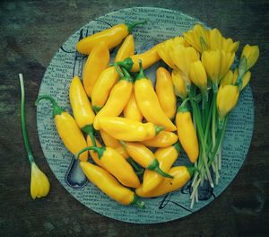 Directly above shot of yellow flowers with jalapeno peppers in plate on table