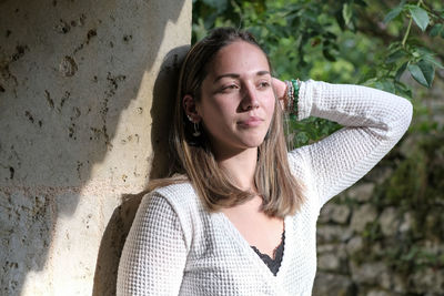 Portrait of young woman standing against plants