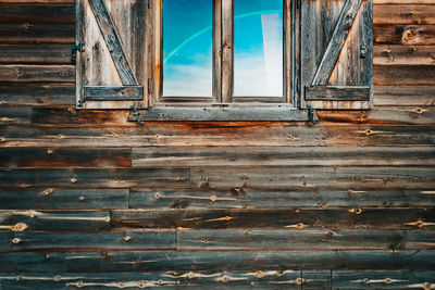 Low angle view of window on old wooden wall