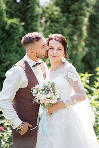 Groom kissing bride outdoors