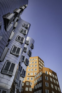 Low angle view of modern buildings against clear blue sky